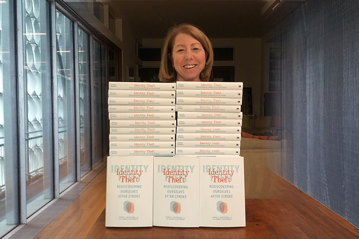 Author Debra Meyerson standing in front of a stack of Identity Theft books