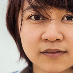 A woman looking straight at the camera. It is part of a collage of 10 faces.