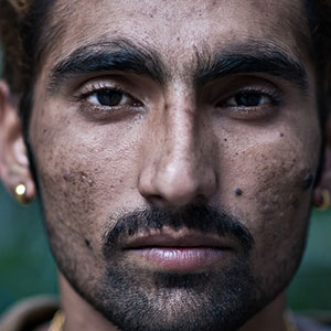 A man looking straight at the camera. It is part of a collage of 10 faces.