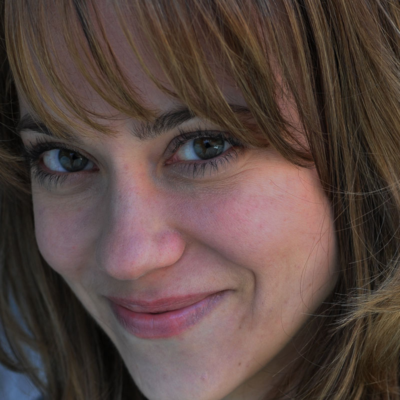 White woman with brown hair and bangs smiling