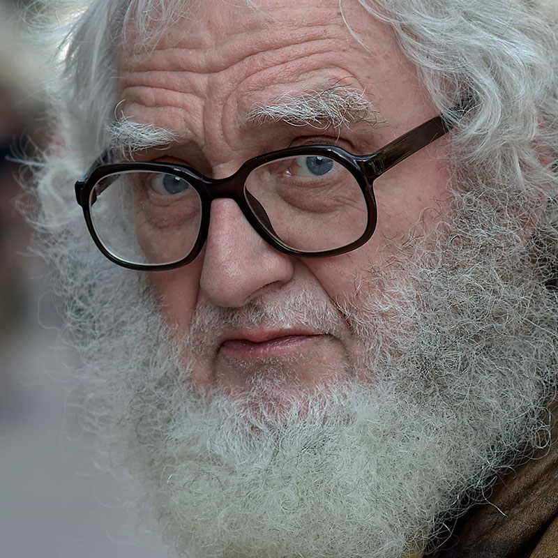 Older white man with a thick beard and black framed glasses